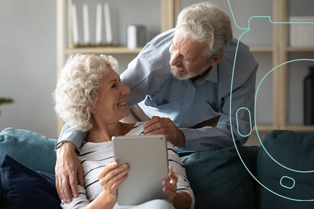 Ältere Frau hält Tablet in der Hand und schaut dabei glücklich zu ihrem Mann hoch, daneben eine stilisierte Toilettengrafik des EKG-seats.
