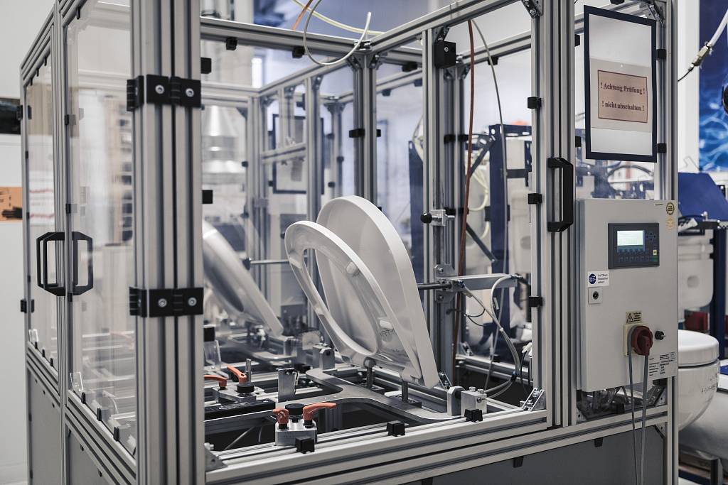 Eine automatisierte Prüfstation testet WC-Sitze in einer industriellen Umgebung.